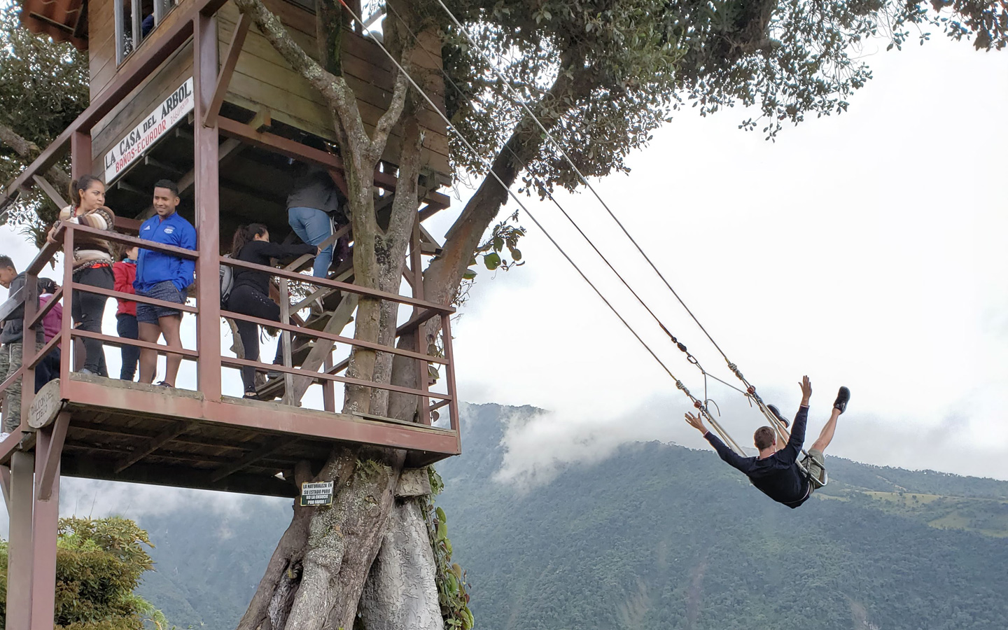 A Spanish student swinging out over a mountain at the Casa del Arbol of Baños