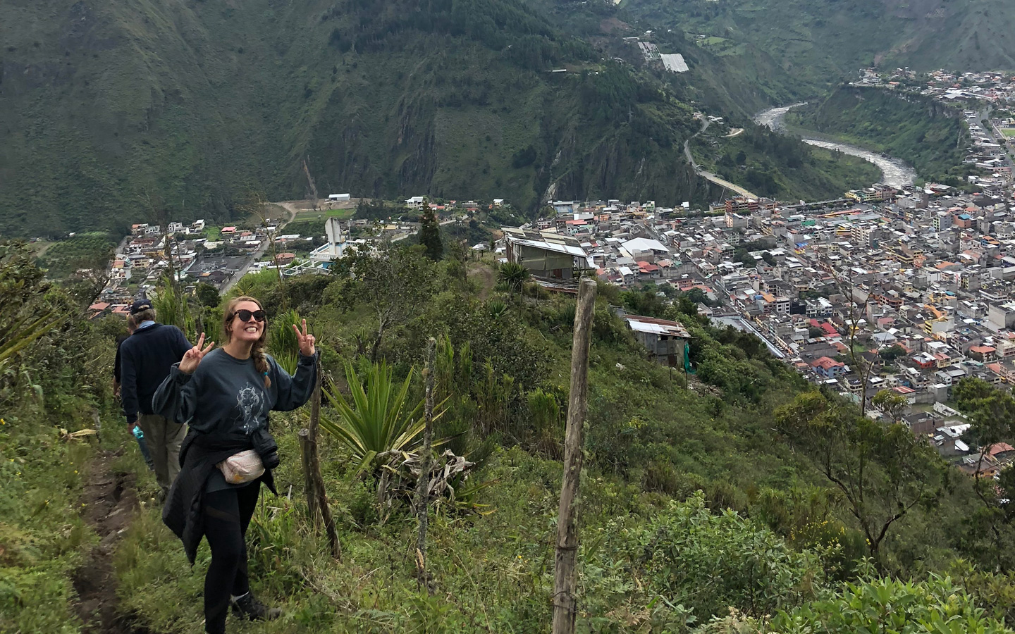 A student hiking with an overlook of the town of Baños